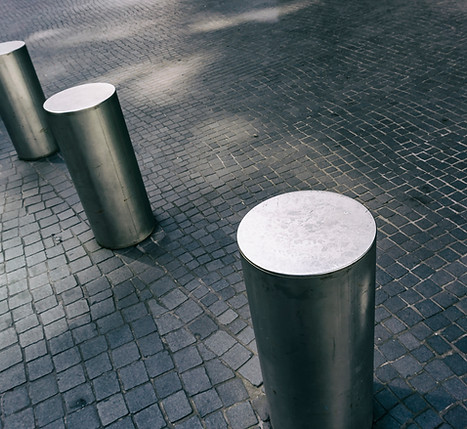 Close-Up of Row of Stainless Steel Bollards on Gray Tiled Pavement